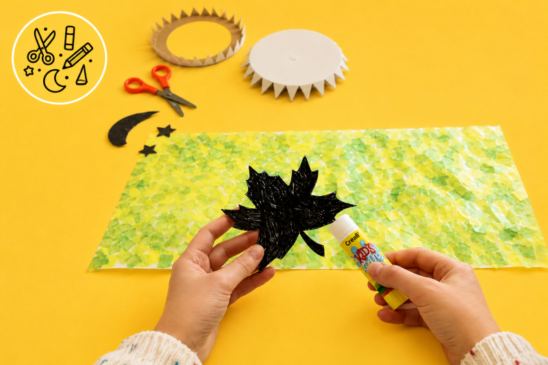 Ein Laternenbogen wird mit einer Blatt-Silhouette beklebt
